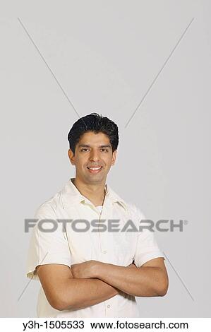 Stock Image - Studio shot of young pakistani man, arms crossed. Fotosearch