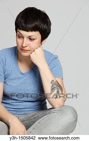 Stock Image - Studio shot of young tattooed woman. Fotosearch