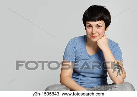 Stock Image - Studio shot of young tattooed woman. Fotosearch