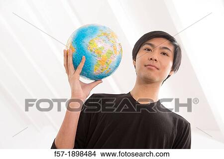 Successful young Asian man holding a globe View Large Photo Image Picture - Successful young Asian man holding a globe. Fotosearch