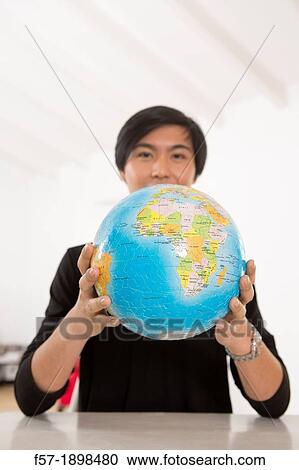 Successful young Asian man holding a globe View Large Photo Image Stock Image - Successful young Asian man holding a globe. Fotosearch