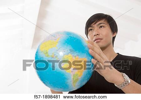 Successful young Asian man holding a globe View Large Photo Image Stock Image - Successful young Asian man holding a globe. Fotosearch