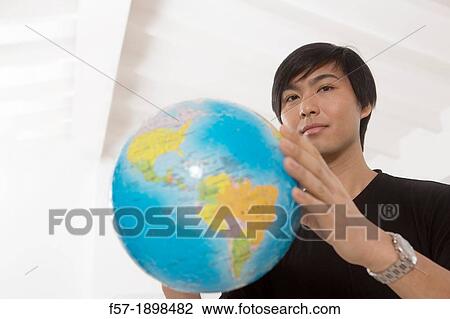 Successful young Asian man holding a globe View Large Photo Image Stock Image - Successful young Asian man holding a globe. Fotosearch