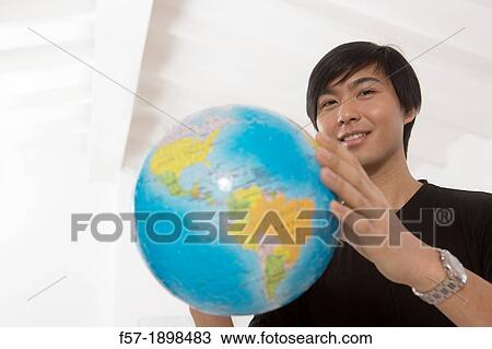 Successful young Asian man holding a globe View Large Photo Image Stock Image - Successful young Asian man holding a globe. Fotosearch