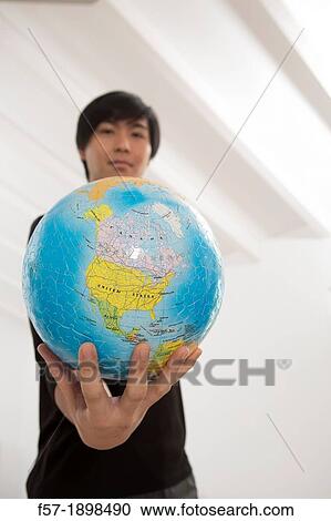 Successful young Asian man holding a globe View Large Photo Image Stock Image - Successful young Asian man holding a globe. Fotosearch