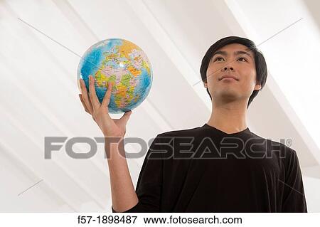 Stock Photo - Successful young Asian man holding a globe. Fotosearch