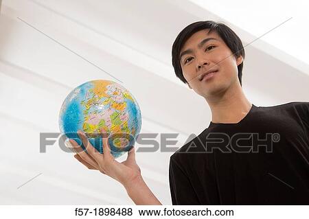 Successful young Asian man holding a globe View Large Photo Image Stock Photo - Successful young Asian man holding a globe. Fotosearch