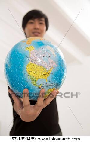 Successful young Asian man holding a globe View Large Photo Image Stock Photo - Successful young Asian man holding a globe. Fotosearch