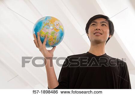 Successful young Asian man holding a globe View Large Photo Image Stock Photograph - Successful young Asian man holding a globe. Fotosearch