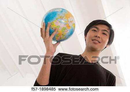 Successful young Asian man holding a globe View Large Photo Image Stock Photography - Successful young Asian man holding a globe. Fotosearch