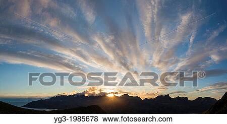 Stock Photo - Sun setting behind mountains of Flakstadoy from Skottind, Vestv? goya, Lofoten islands, Norway. Fotosearch