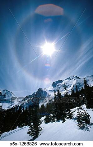 Stock Photograph - Sundog and lens flare in sky over Never Summer mountains in winter, Colorado, USA. Fotosearch