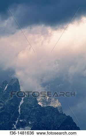 Stock Photograph - Sunlight on storm clouds near the summit of the Grand Tetons, Grand Teton Nat? l Pk, WYOMING. Fotosearch