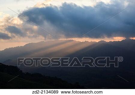 Stock Photo - Sunrise and light beams over forested hillsides. Doi Pha Hom Pok National Park. Thailand.. Fotosearch