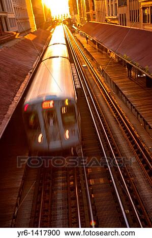 Stock Image - Sunrise illuminates a train in the Chicago rapid transit system known as the? L? in Chicago, IL, USA. Fotosearch