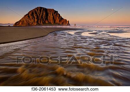 Stock Image - Sunrise light on Morro Rock over Little Morro Creek, Morro Strand State Beach, Morro Bay, California.. Fotosearch