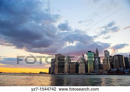 Stock Image - Sunset behind the Downtown Manhattan Skyline and the New York Harbor. Fotosearch