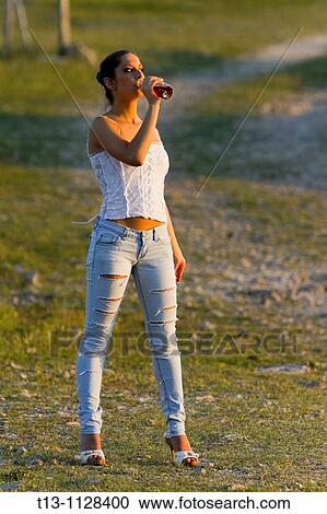Sunset lit, attractive young woman is drinking cold tea from a plastic bottle View Large Photo Image Stock Image - Sunset lit, attractive young woman is drinking cold tea from a plastic bottle. Fotosearch