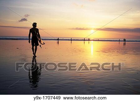 Sunset on Kuta Beach, surfers carry their surfboards from the ocean after a long day riding the waves View Large Photo Image Stock Photo - Sunset on Kuta Beach, surfers carry their surfboards from the ocean after a long day riding the waves. Fotosearch