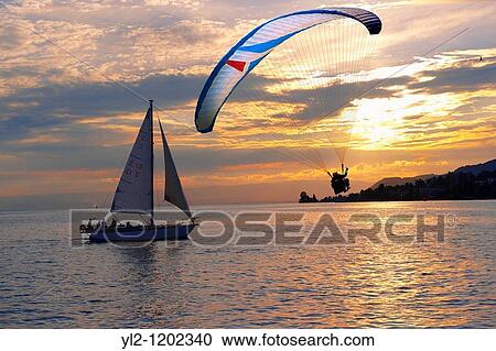 Stock Image - Sunset over Lac Leman lake Geneva with paragliders - Montraux Switzerland. Fotosearch