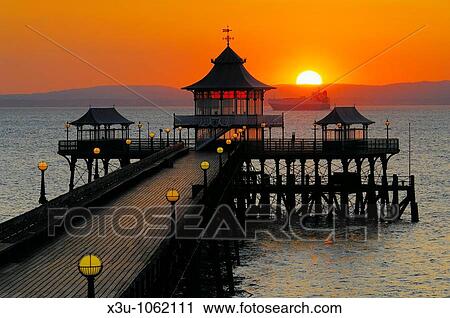 Stock Image - Sunset over the pier in the Bristol Channel at the seaside town of Clevedon in Somerset, England. Fotosearch