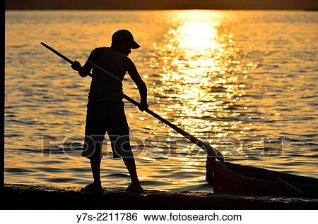 Stock Photograph - Sunset silhouette of boy, El Peten, Flores, Lago de Peten Itza, Guatemala, Central America.. Fotosearch
