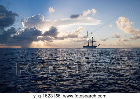 Stock Photograph - Sunset with Sailboat, South Pacific. Fotosearch