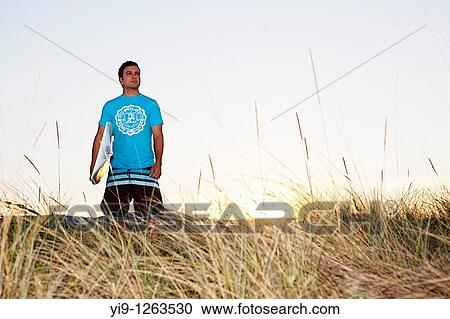 Stock Image - Surfer looking out to sea. Fotosearch