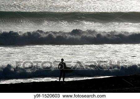Stock Image - Surfer waiting the best wave - Kuta Beach - Bali. Fotosearch