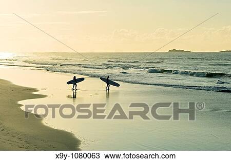 Surfers carrying surfboards walking along sandy beach shoreline evening light summer White Rocks Strand, Portrush, Ireland View Large Photo Image Stock Image - Surfers carrying surfboards walking along sandy beach shoreline evening light summer White Rocks Strand, Portrush, Ireland. Fotosearch