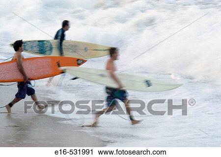 Surfers racing into the water View Large Photo Image Stock Image - Surfers racing into the water. Fotosearch