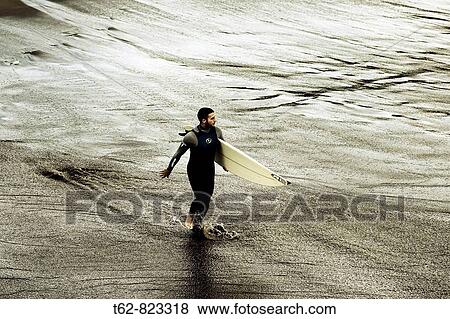 Surfing Young man entering the water View Large Photo Image Stock Photo - Surfing Young man entering the water. Fotosearch