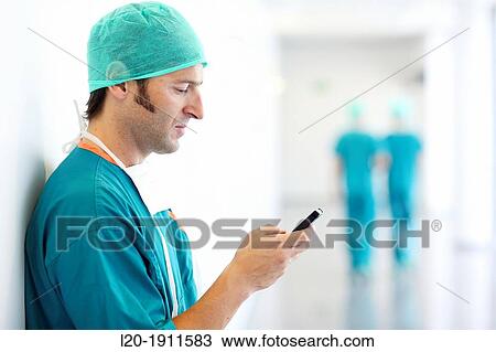 Stock Image - surgeon with smartphone in the operating room hallway, Onkologikoa Hospital, Oncology Institute, Case Center for prevention, diagnosis and treatment of cancer, Donostia, San Sebastian, Gipuzkoa, Basque Country, Spain. Fotosearch