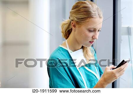 Stock Photo - surgeon with smartphone in the operating room hallway, Onkologikoa Hospital, Oncology Institute, Case Center for prevention, diagnosis and treatment of cancer, Donostia, San Sebastian, Gipuzkoa, Basque Country, Spain. Fotosearch