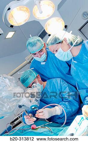 Stock Image - Surgeons during hearing operation at otorhinolaryngology operating room of hospital. Fotosearch