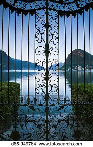 Switzerland, Ticino, Lake Lugano, Lugano, Parco Civico gate view of Monte San Salvador, dawn View Large Photo Image Picture - Switzerland, Ticino, Lake Lugano, Lugano, Parco Civico gate view of Monte San Salvador, dawn. Fotosearch