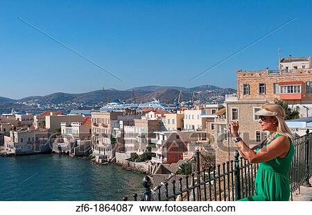 Syros Greece Islands a woman tourist camera in Hermoupolis capital with white buildings water ocean and classic architecture View Large Photo Image Stock Photo - Syros Greece Islands a woman tourist camera in Hermoupolis capital with white buildings water ocean and classic architecture. Fotosearch