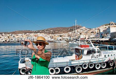 Syros Greece Islands in Hermoupolis capital in marina harbor boats ships port white buildings water boating fishing architecture with tourist lady in green with camera taking pictures View Large Photo Image Stock Image - Syros Greece Islands in Hermoupolis capital in marina harbor boats ships port white buildings water boating fishing architecture with tourist lady in green with camera taking pictures. Fotosearch