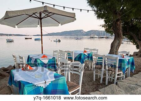 Table and chairs on the waterfront at sunset, Adamas, Milos Island, Dodecanese, Greece View Large Photo Image Stock Photo - Table and chairs on the waterfront at sunset, Adamas, Milos Island, Dodecanese, Greece. Fotosearch