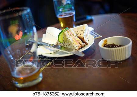 Table in a pub with sandwich, pickle and beer View Large Photo Image Stock Image - Table in a pub with sandwich, pickle and beer. Fotosearch