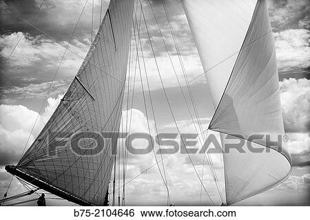 Stock Photograph - Tackle Bermudiana or Marconi of a classic sailboat. Main sail and spinnaker and clouds on the background.. Fotosearch