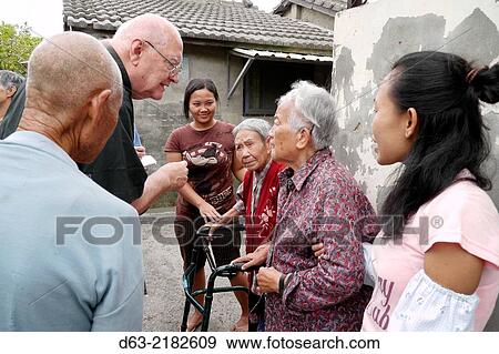 TAIWAN. American missionary priests visiting retired KMT soldiers and their families at Chang Chyu village, Taichung. Liu Yang Syan (red) and Dzou Feng Jeng (glasses on head). With Indonesian care giver Susyant (pink shirt). View Large Photo Image Stock Photo - TAIWAN. American missionary priests visiting retired KMT soldiers and their families at Chang Chyu village, Taichung. Liu Yang Syan (red) and Dzou Feng Jeng (glasses on head). With Indonesian care giver Susyant (pink shirt).. Fotosearch