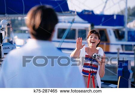 Stock Photography - taking a photo of her husband at the marina. Fotosearch