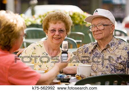 Stock Image - Taking a photo of seniors with camera phone. Fotosearch
