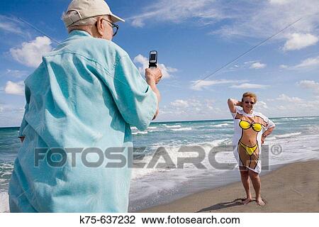 Taking picture of wife in humorous tee shirt at beach View Large Photo Image Stock Image - Taking picture of wife in humorous tee shirt at beach. Fotosearch