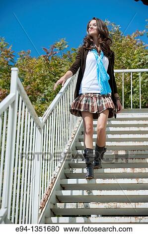 Tall brunette woman in a short skirt and boots waking down a flight of white steps looking away from the camera, blue sky in background View Large Photo Image Stock Image - Tall brunette woman in a short skirt and boots waking down a flight of white steps looking away from the camera, blue sky in background. Fotosearch