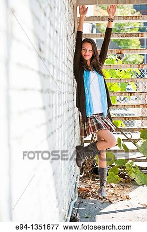 Tall brunette woman in a short skirt and boots standing next to a white wall with arms raised to steps above View Large Photo Image Stock Photo - Tall brunette woman in a short skirt and boots standing next to a white wall with arms raised to steps above. Fotosearch