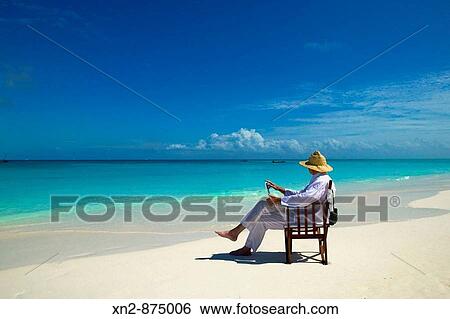 Tanzania. Mnemba Island. Resort Guest on his laptop on the exquisite beach that fronts the resort. View Large Photo Image Stock Photograph - Tanzania. Mnemba Island. Resort Guest on his laptop on the exquisite beach that fronts the resort.. Fotosearch