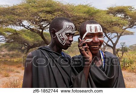 Tanzania Serengeti Africa Masai Maasai boys talking on cell phone in black clothes from circumcision ceremony with face paint 7 View Large Photo Image Picture - Tanzania Serengeti Africa Masai Maasai boys talking on cell phone in black clothes from circumcision ceremony with face paint 7. Fotosearch
