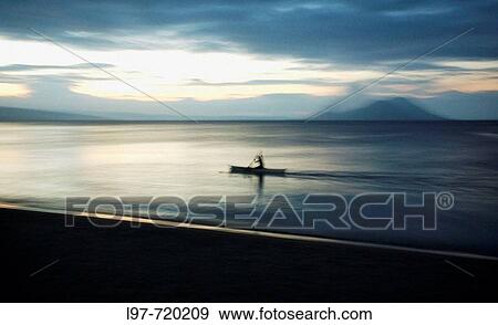 Tavurvur Volcano in the distance, a fisherman rows offshore near the town of Kokopo which has since become the main town for East New Britain since the eruption of 1994 which devestated the former capital of Rabaul View Large Photo Image Stock Photo - Tavurvur Volcano in the distance, a fisherman rows offshore near the town of Kokopo which has since become the main town for East New Britain since the eruption of 1994 which devestated the former capital of Rabaul. Fotosearch